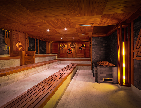 Przytulna sauna, inspirowana stylem wikingów, z drewnianymi ławkami i ciepłym, przyjemnym oświetleniem.
